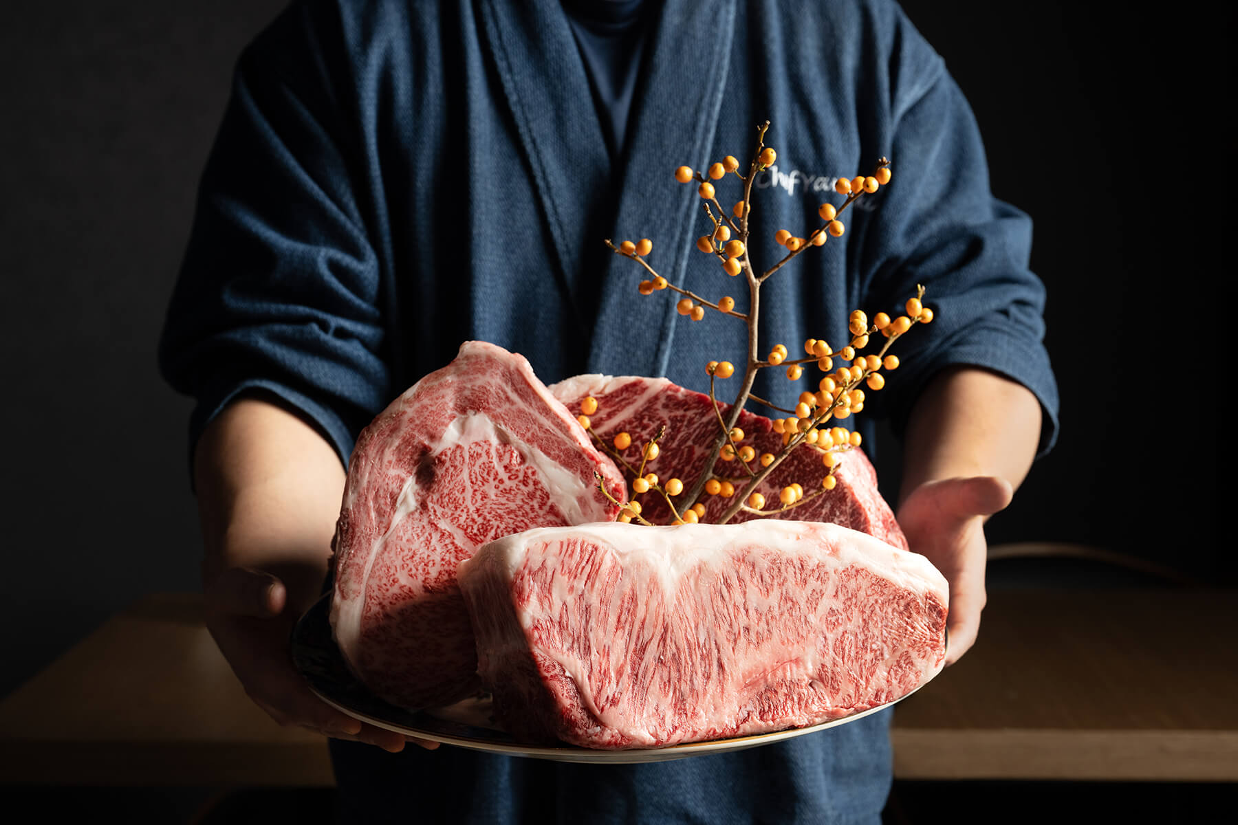 Chef Ken Yamasaki holding a platter of marbled Wagyu cuts